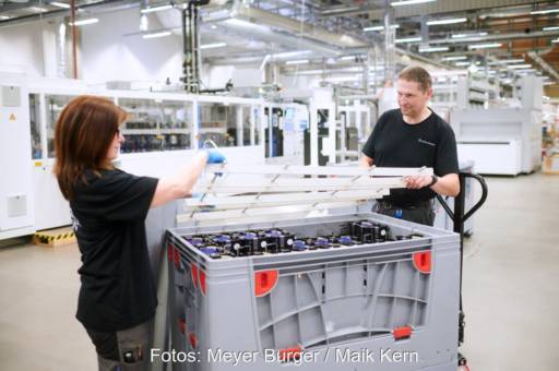 Eine Frau und ein Mann verstauen Solarzellen aus einem Werk in einer Box.