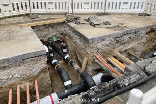 Eine aufgerissene Straße mit neuen Leitungen für ein Wärmenetz. Zu sehen sind zudem weitere Versorgungsleitungen. Symbolbild für GEG und kommunale Wärmeplanung.