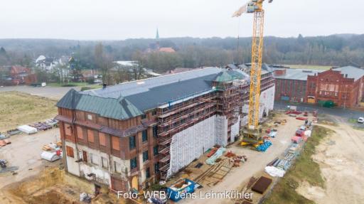Das historische Gebäude der Bremer Wollkämmerei in Bremen-Nord mit Baukran, die Wärmeversorgung erfolgt über ein neues Wärmenetz.