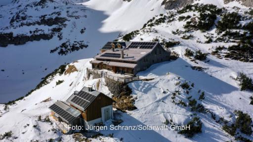 Eine Hüttenanlage in den Alpen mit Solarmodulen auf den Dächern und Schneeumgebung