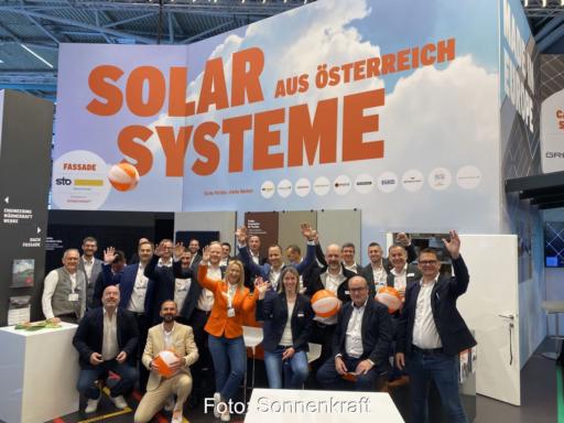 Das Team von Sonnenkraft winkend an einem Messestand.