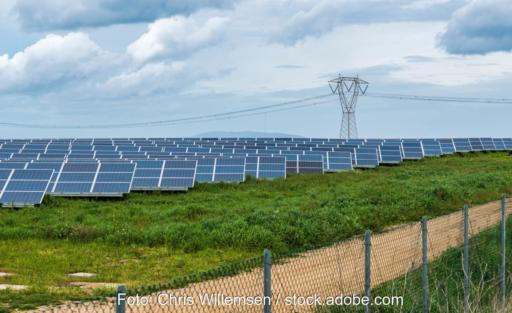 Freiflächen-Solarpark vor Stromleitung.