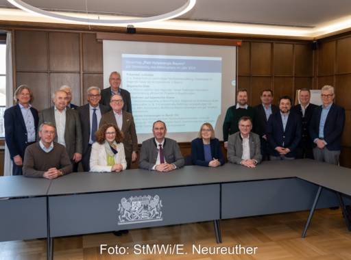 Eine Gruppe Männer und zwei Frauen sitzen bzw stehen hinter einem Tisch - Bayerns Pakt für Holzenergie.