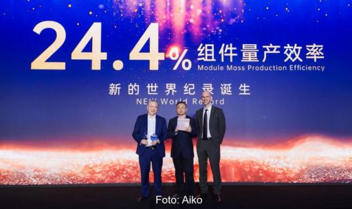 Im Bild Offizielle vor einer Leinwand mit der Aufschrift 24,4 %, dem Wirkungsgrad vom Rückkontakt-Modul Comet von Aiko.