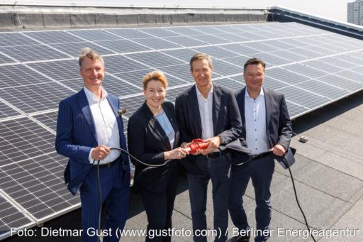 Die vier Verantwortlichen stehen auf dem Dach eines Gebäudes vor einer PV-Anlage