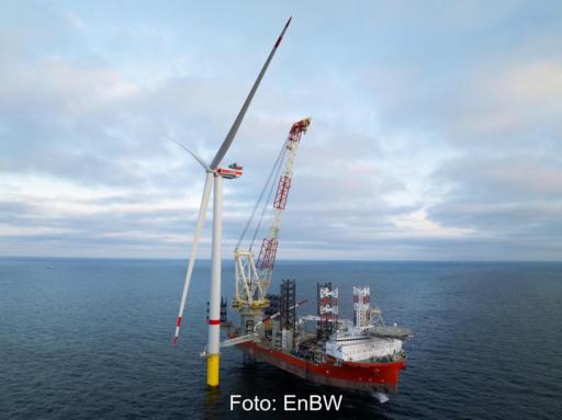 Ein Schiff liegt neben einer Offshore-Windkraftanlage