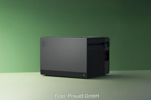 Ein schwarzer Batteriespeicher steht vor einem waldgrünen Hintergrund.