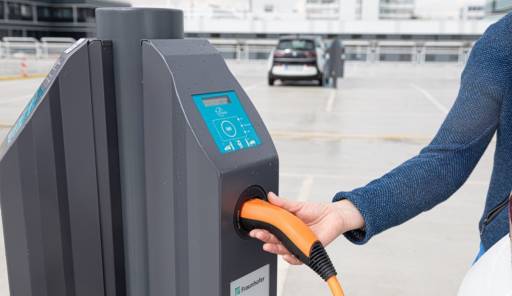 Im Bild eine Hand mit Stecker an einer Ladestation, die Integration von Ladestationen in gewerbliche DC-Netze kann zu mehr Energieeffizienz führen.