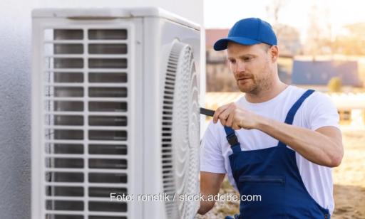 Ein Handwerker montiert eine Luftwärmepumpe, der Kostenvorteil der Wärmepumpe gegenüber der Gasheizung ist deutlich.