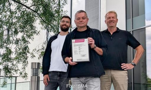 SMA-Mitarbeiter präsentieren das Zertifikat für die Einhaltung der Cybersicherheit nach der Norm ETSI EN 303 645.