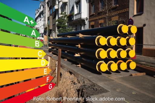 Eine Straße, dort rechts im Bild Rohre für die Fernwärme, die noch nicht in der aufgerissenen Straße verlegt wurden. Links die farbige Darstellung der Effizienzstufen. Beides als Symbol für die kommunale Wärmeplanung.