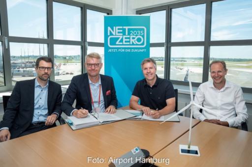 Vier Herren bei Vertragsunterzeichnung. Im Hintergrund Start- und Landebahn.