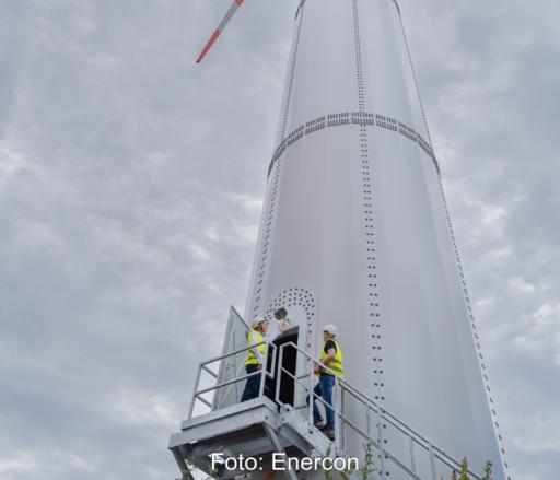 Zwei Personen am Treppenaufgang zu einer Windenergieanlage.