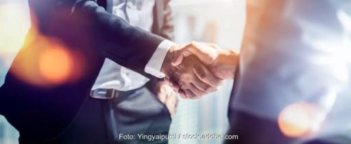 Das Bild zeigt im Anschnitt einen Handschlag zwischen zwei Männern in Anzügen als Symbolbild für eine Einigung.