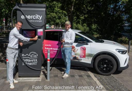 Zwei Personen stehen an einer Ladesäule und bezahlen kontaktlos mit einer Karte.