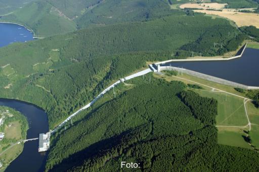 Zusehen ist ein Pumpspeicherwerk aus der Vogelperspektive, welches einen höher gelegenen Stausee mit einem tiefer gelegenen Fluß verbindet.