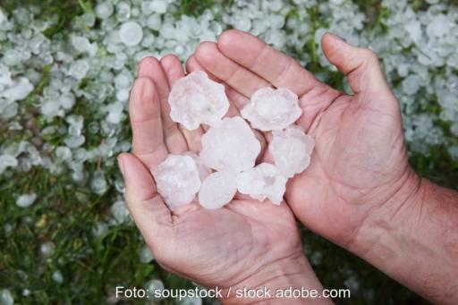Zwei Hände halten große Hagelkörner - Symbol für Hagelschutzklasse für Solarmodule