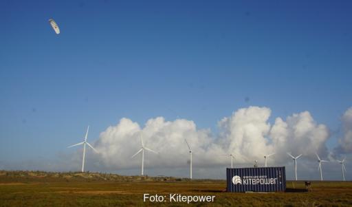 Ein Drachen fliegt vor Windenergieanlagen, Kitepower testet sein Flugwindkraft-System in Irland.