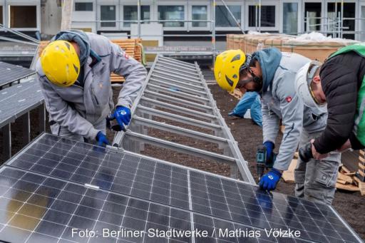 Monteure installieren PV-Module auf Gestellen auf einem Flachdach.
