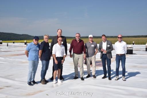 Personengruppe mit u.a. Klaus Vajen, Helgo Schütze, Christian Stadler auf der Kunststoff-Abdeckung des Erdbecken-Wärmespeichers