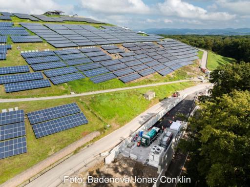 Deponieberg mit PV-Modulen und Tankstelle am Fuß des Hügels.