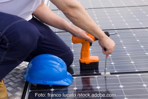 Ein Handwerker schraubt Photovoltaik-Module fest - ein Symbol für die Arbeit am neuen EEG 2027.