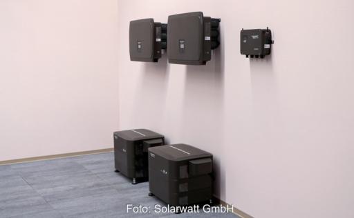 Schwarze Geräte an rosa Wand: Die Clusterbox von Solarwatt kann mehrere Batteriespeicher zu einem Gesamtsystem kombinieren.
