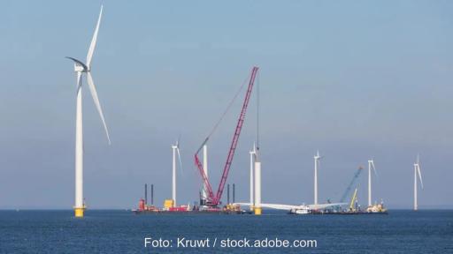 Ein Kran und Windenergieanlagen im Meer, die Offshore-Wind-Branche fordert bessere Rahmenbedingungen.