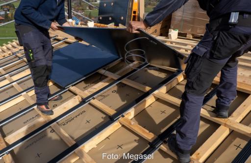 Zwei Installateure auf dem Dach montieren das Level Up Photovoltaik-System für die Dachintegration von Megasol.