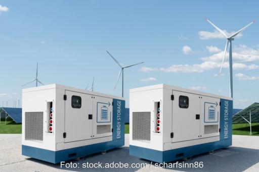 Zwei Energiespeicher vor Wind- und PV-Anlagen.