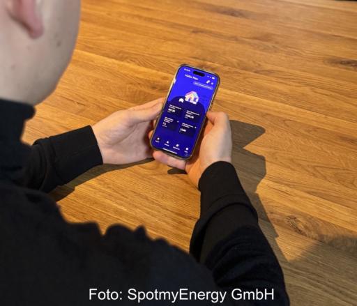 Nuter hält ein Smartphone, das eine App für das Energiemanagement im Haus zeigt.