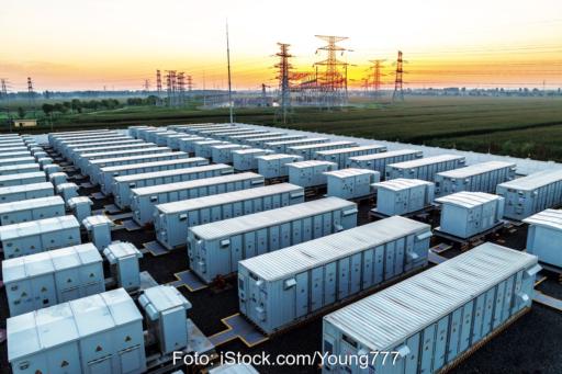 Mehrere Reihen mit Containern (Großspeicher), im Hintergrund Hochspannungsmasten