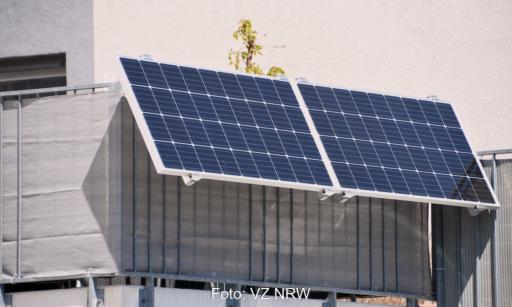 Steckersolargerät an einem Balkon montiert, Solarmodul am Geländer befestigt und über Kabel mit der Wohnung verbunden.