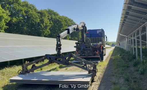 Ein Fahrzeug lädt die Aluminium-Panels für die temporäre Baustraße im Photovoltaik-Solarpark ab.