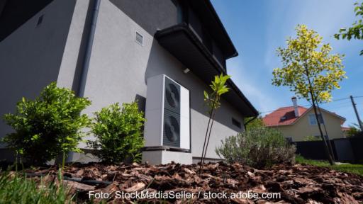 Vor einem Gebäude steht eine Wärmepumpe.