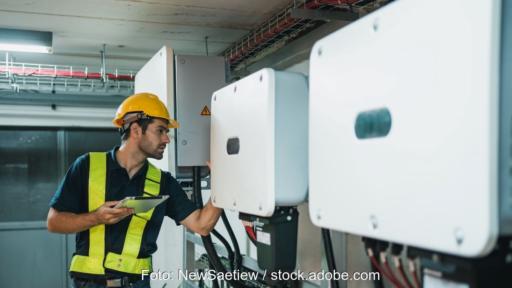 Ein Elektrotechniker prüft Wechselrichter in einem Versorgungskeller.