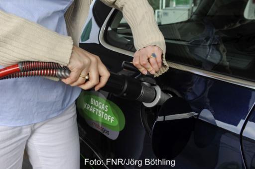Autofahrerin betankt ein Fahrzeug mit Biomethan.