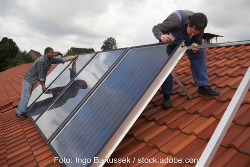 Handwerker installieren Solarthermie auf Dach - Symbolbild