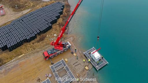 Ein Kran hievt einen Container auf eine künstliche Insel, Bauarbeiten für die schwimmende Solaranlage (Floating-PV) auf dem Kühlsee in Iffezheim.