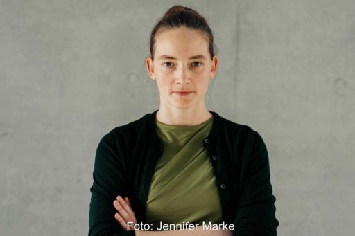 Portraitfoto Violetta Bock vor grauer Wand mit verschränkten Armen