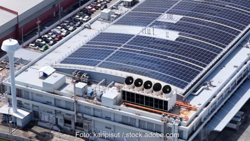 Gebäude eines Rechenzentrums. Auf dem Dach sind PV-anlagen und große Ventilatoren von Kältemaschinen zu sehen.