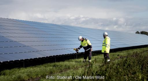 Zwei Menschen in gelber Arbeitskleidung inspizieren Solarmodule in einem Photovoltaik-Solarpark, Statkraft verkauft Solarstrom über einen Solar-PPA an die Wuppertaler Stadtwerke.