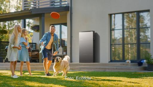 Eine Familie im Garten, an der Hauswand ein Photovoltaik-Batteriespeicher Ecoflow Ocean 2.