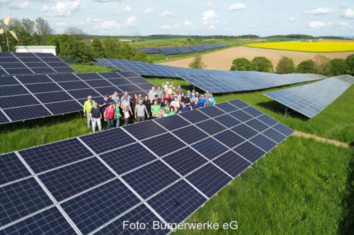 Menschentraube in einem Bürgersolarpark aus der Luft fotografiert