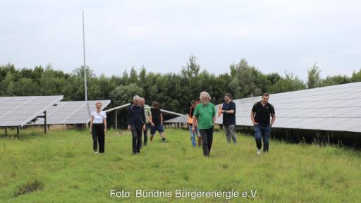Personen, die für Bürgerenergie stehen, posieren vor Freiflächenparks.