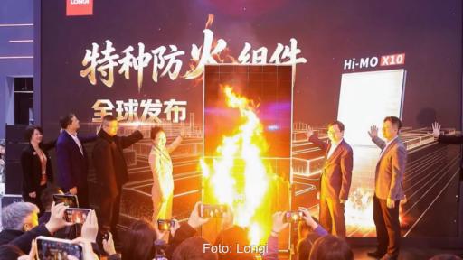 Mehrere Personen bei einer Veranstaltung neben einem PV-Modul, das den Flammen ausgesetzt ist.