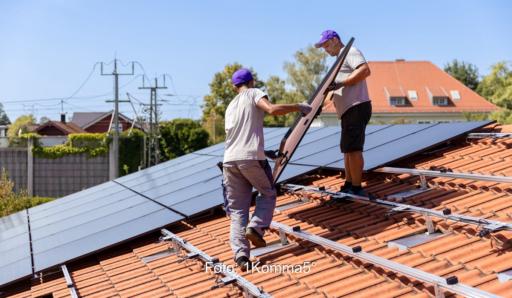 Zwei Installateure tragen ein Solarmodul auf das Dach, 1Komma5° hat ermittelt, welche Auswirkungen die PV-Strom-Direktvermarktung auf den Erlös der Verbraucher:innen hätte.