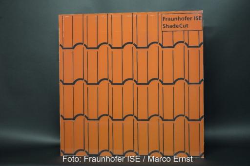 Auf dem Foto ist eine Folie zu sehen, die auf einer etwa quadratischen Fläche rote Dachziegel imitiert, der Hintergrund ist dunkelgrau.