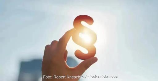 Eine Hand hält ein Paragrafen-Zeichen vor die Sonne, der BNE fordert die flexible Netznutzung von Windenergie, Photovoltaik und Batteriespeichern im EEG zu regeln.