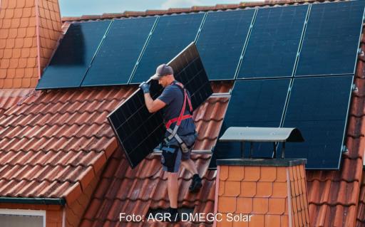 Ein Installateur auf dem Dach trägt ein Photovoltaik-Modul, ergonomische Solarmodule erleichtern das Handling.